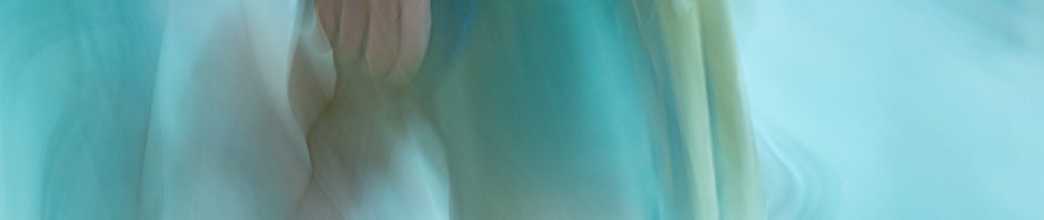 A blurred impression of a woman walking by, just the lower torso in a turquoise dress, and calves, with arm and hand nearest the camera in motion too. The bluey-green pale tones predominate, with just the flesh tones varying.